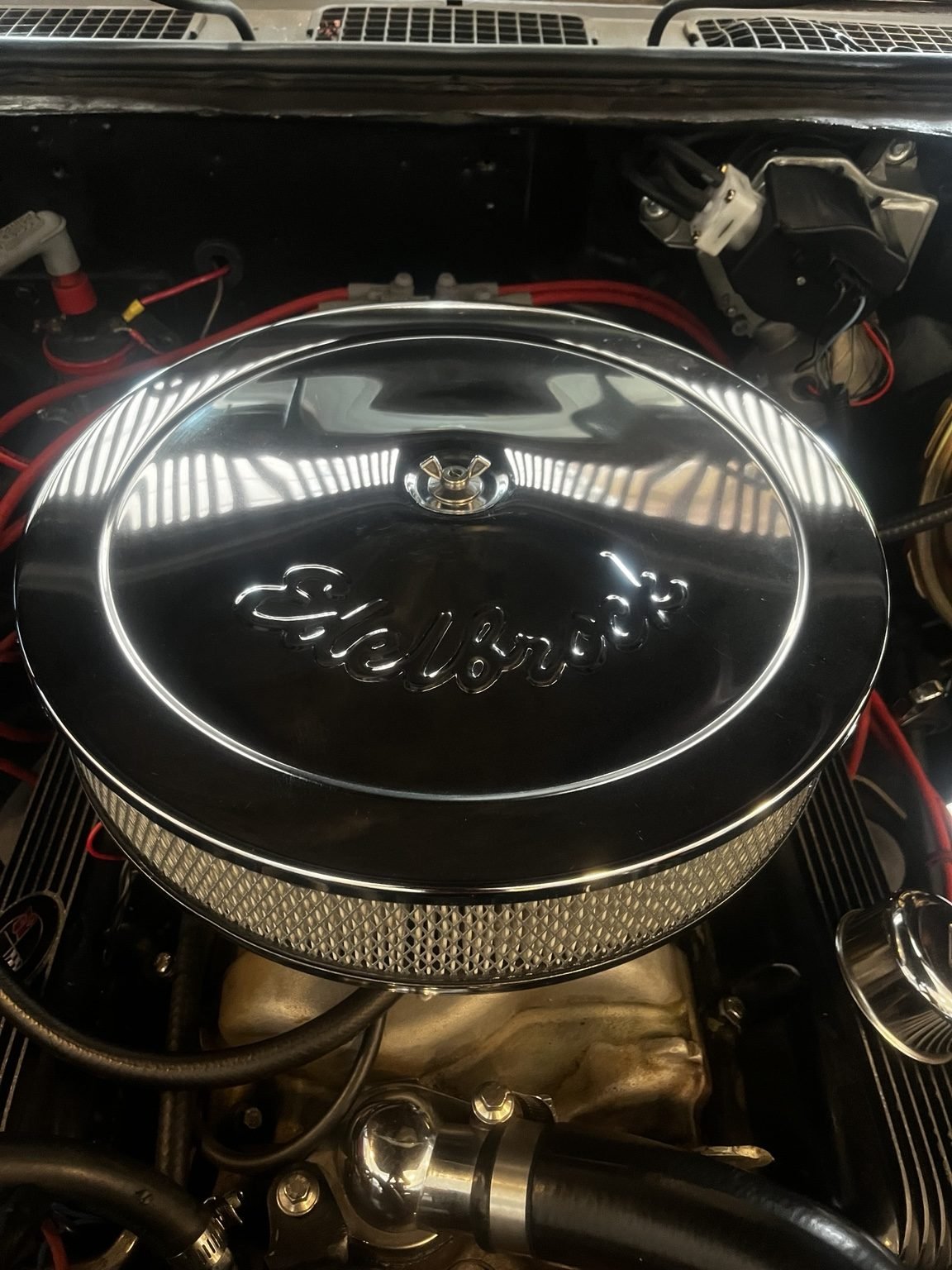 Professinal engine bay detailing on a classic Chevrolet with a polished Edelbrock air cleaner and restored engine components.