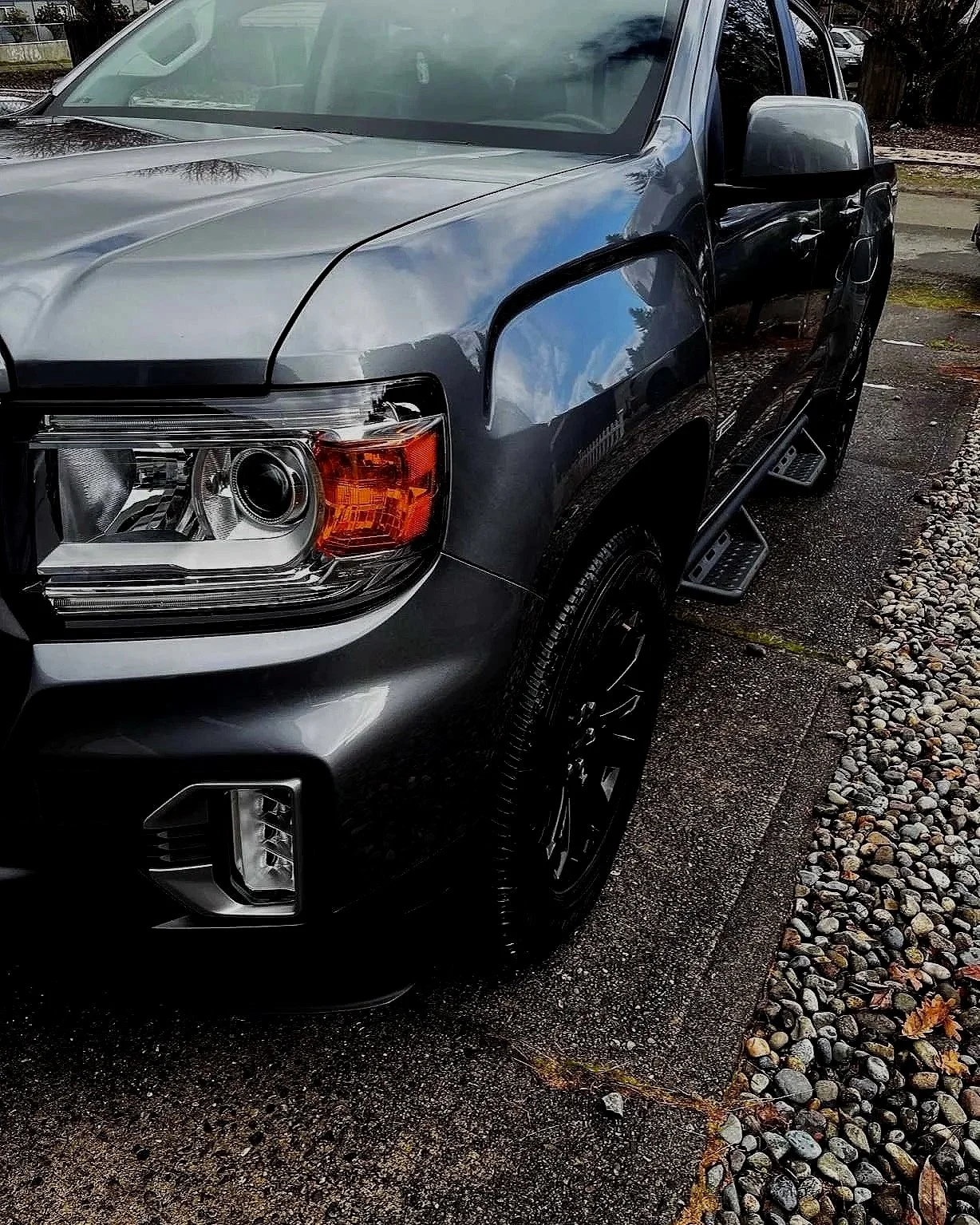 Gray GMC Canyon pickup truck showing a clear, restored front headlight after professional headlight restoration by Bryanz Auto Detailing