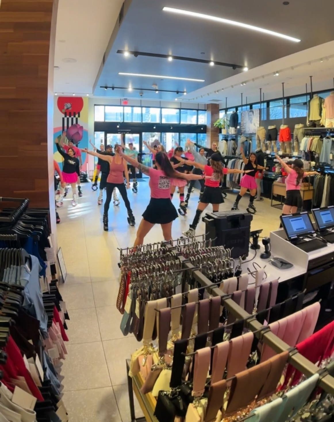 Group fitness class in store, women in workout attire, shelves with clothing and accessories.
