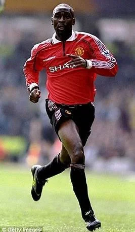 Andy Cole player in red jersey running on the field.
