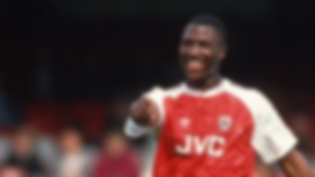 Blurry image of a soccer player wearing a red and white Arsenal FC jersey with JVC logo on the front.