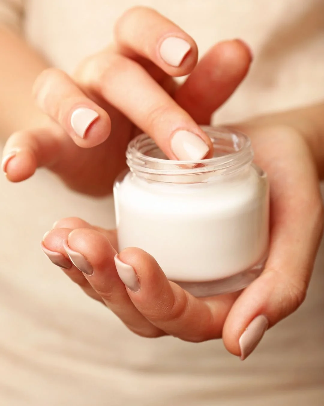 Woman’s hands opening a jar of rich white face or body cream