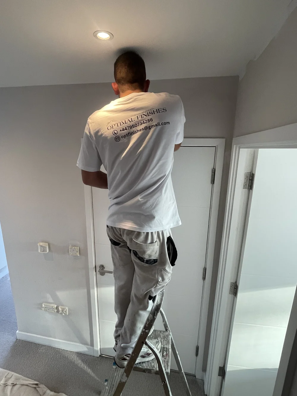 Optimal Finishes decorator painting a ceiling edge