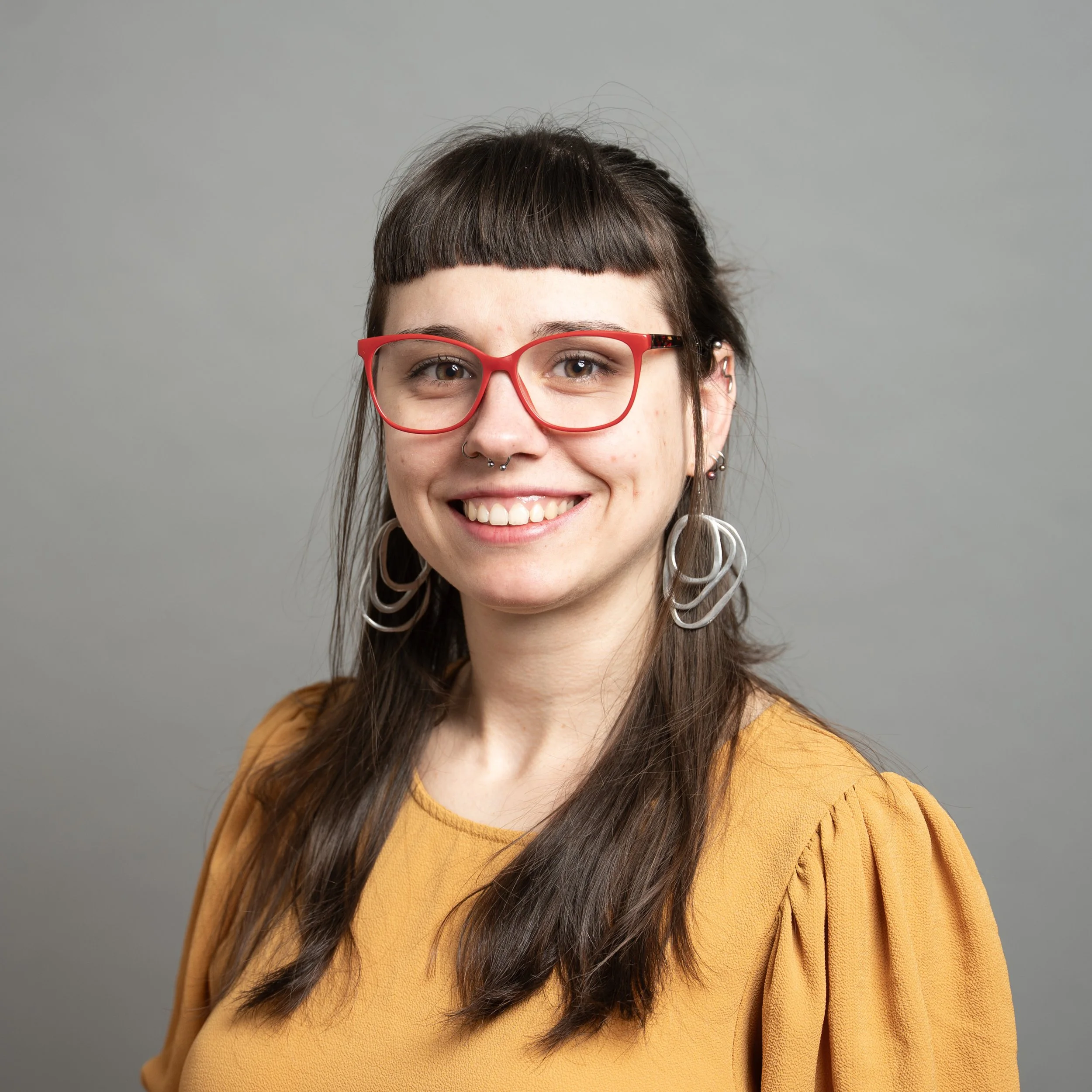 portrait of a young woman with red glasses and long dark hair
