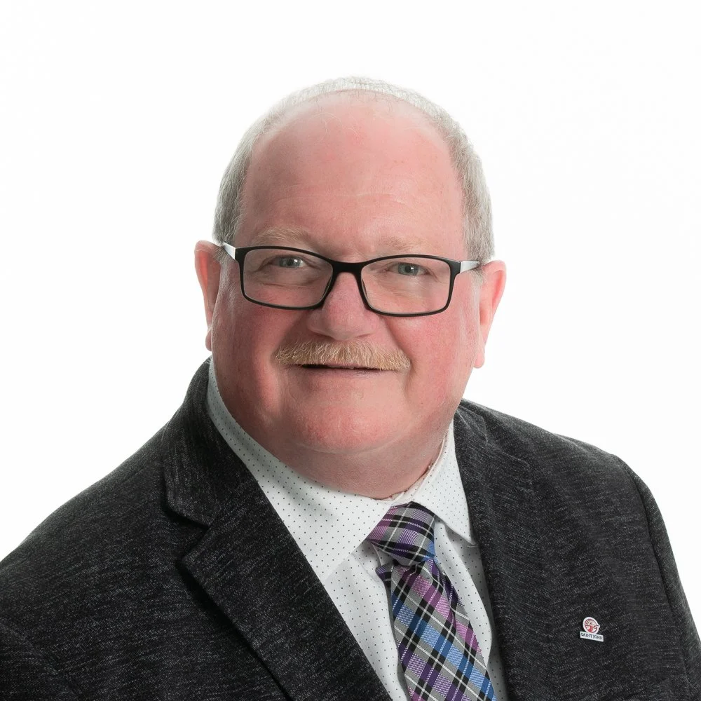 Portrait of a middle-aged man with glasses, a mustache, wearing a suit and tie, against a white background.
