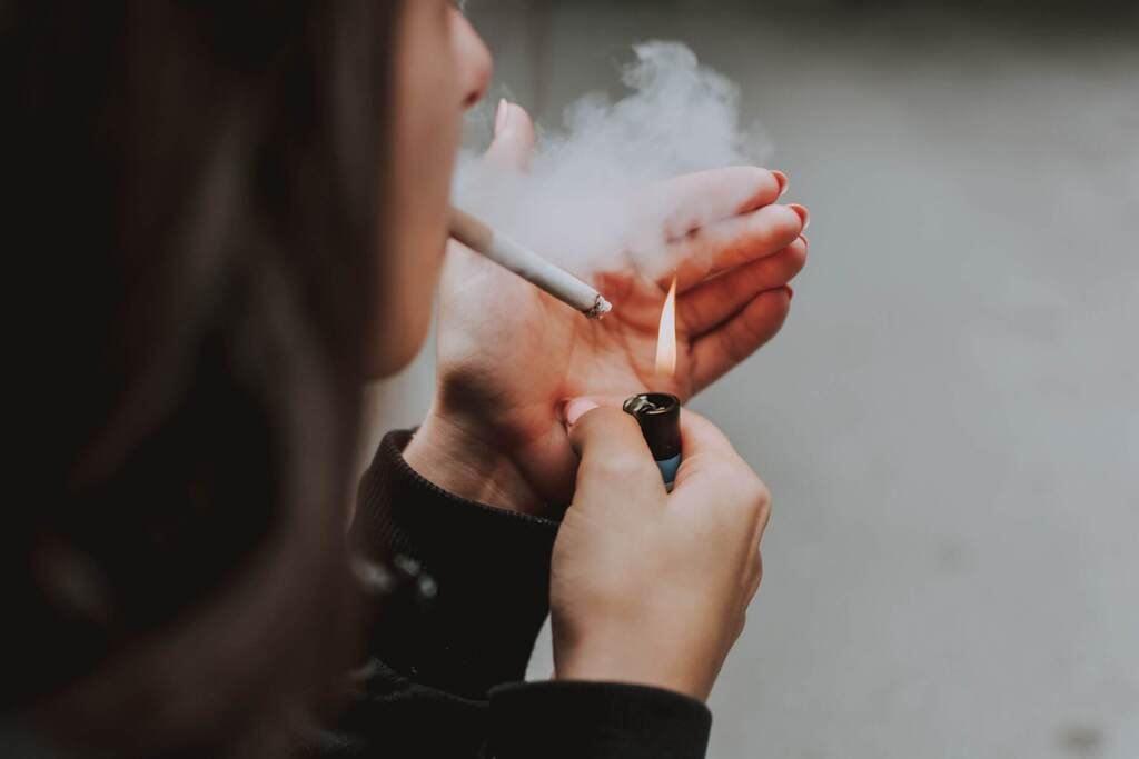 Personne allumant une cigarette avec un briquet.