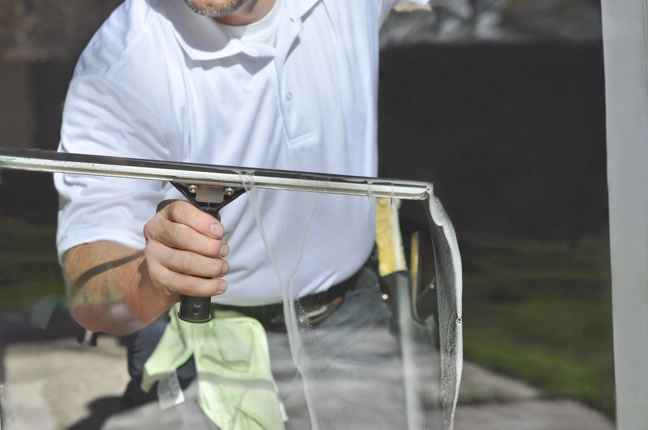 Man maakt een raam schoon met een wisser op een schuifraam.