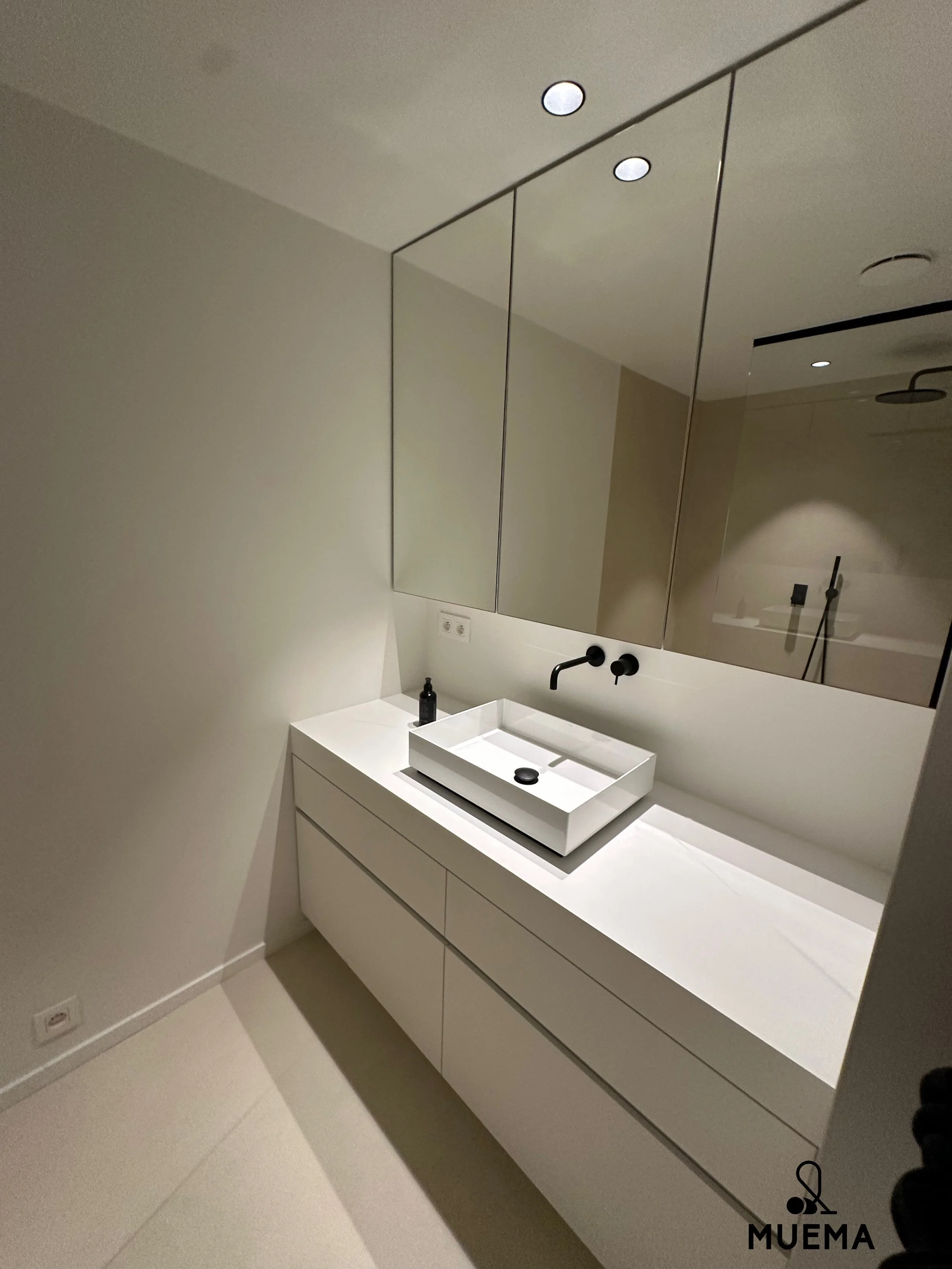 Moderne badkamer met witte wastafel, groot spiegel en inbouwkast.