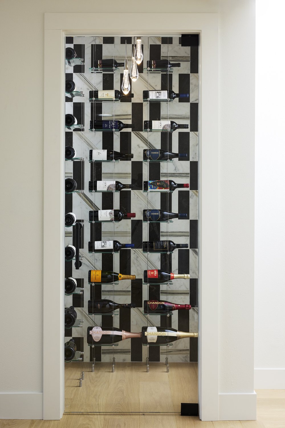 Wall-mounted wine bottles and glasses display with black and white checkered background.