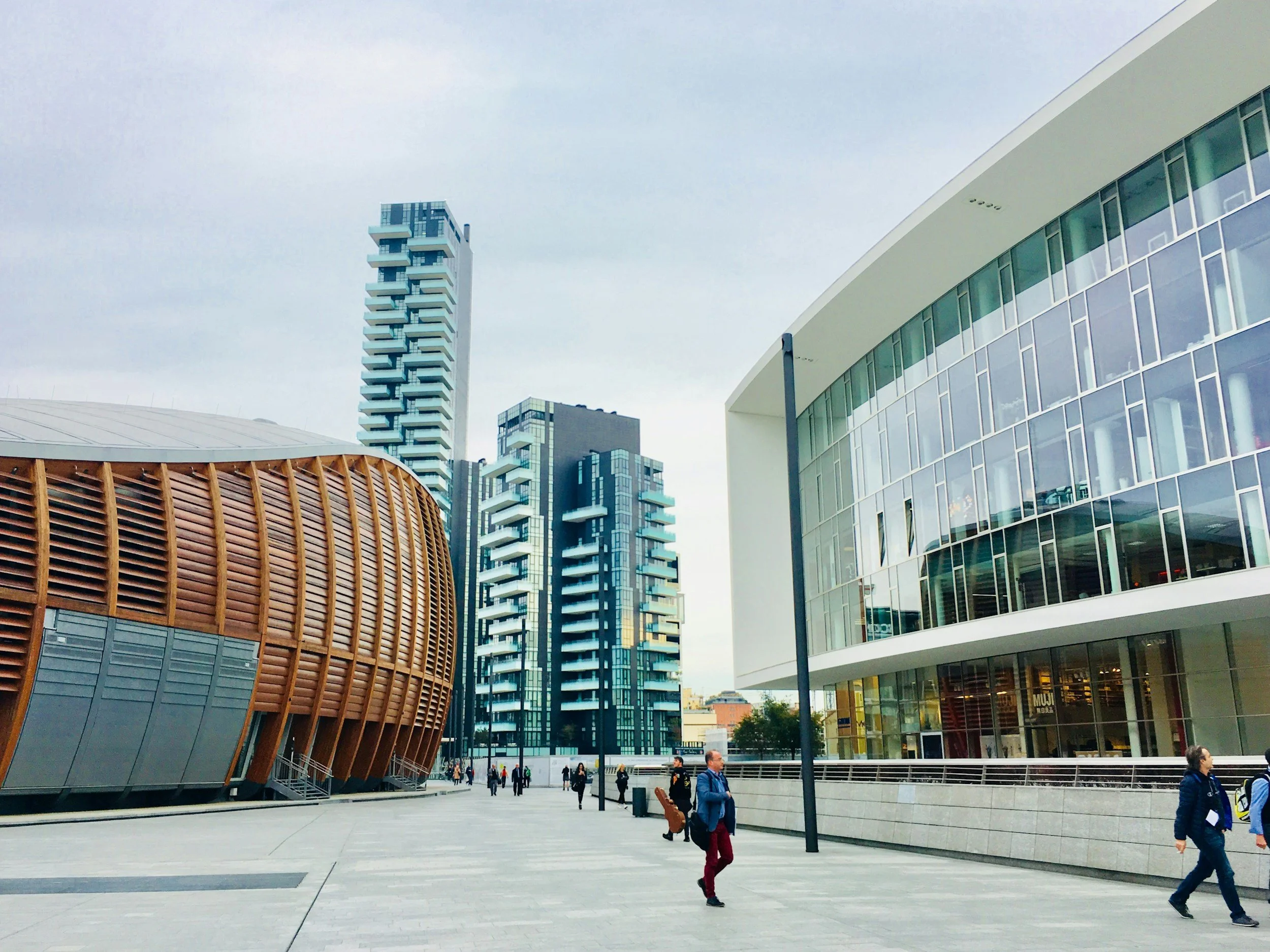 Modern cityscape with unique architectural buildings and pedestrians walking on a spacious plaza