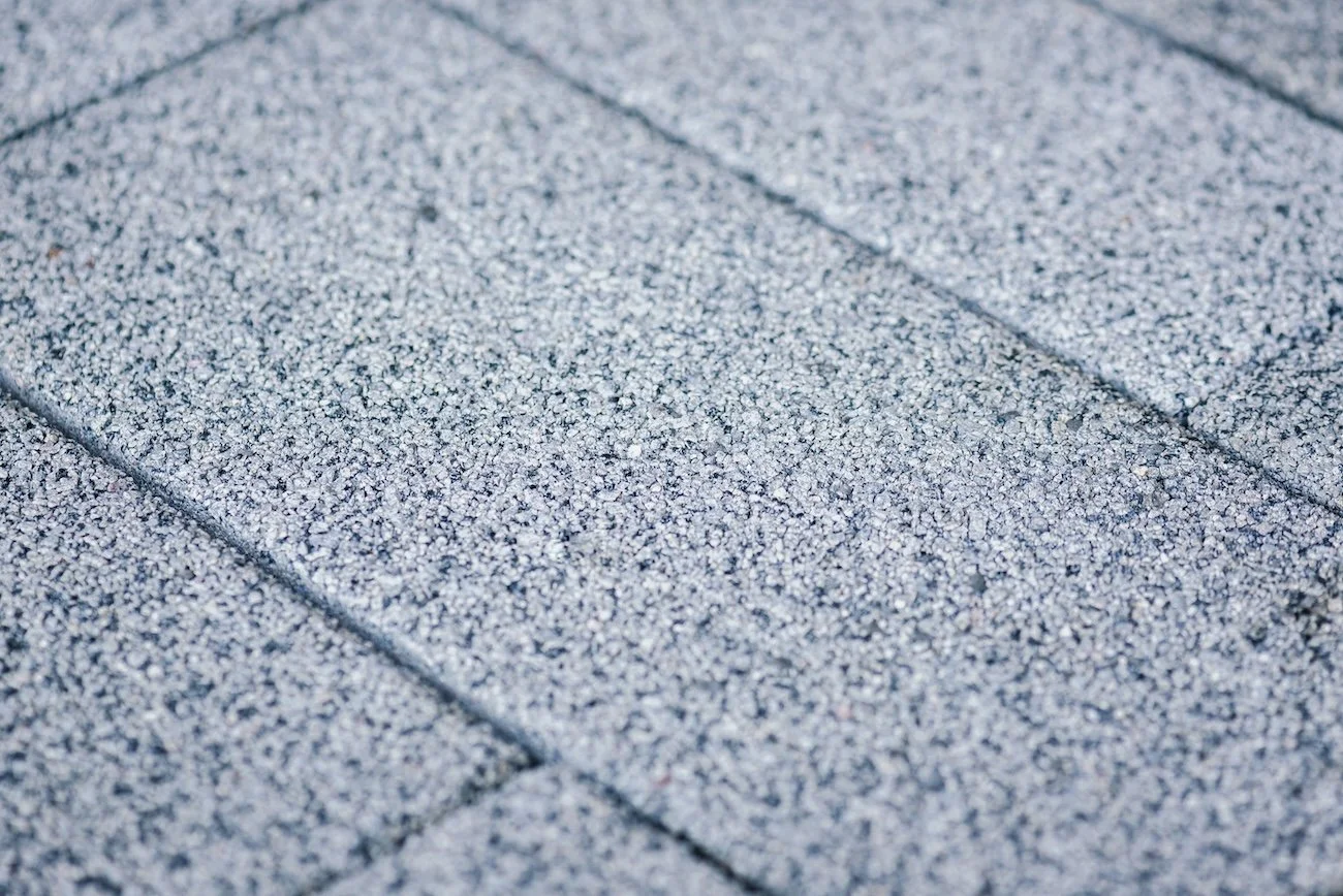 Close-up of gray asphalt shingles with a rough, granular surface.
