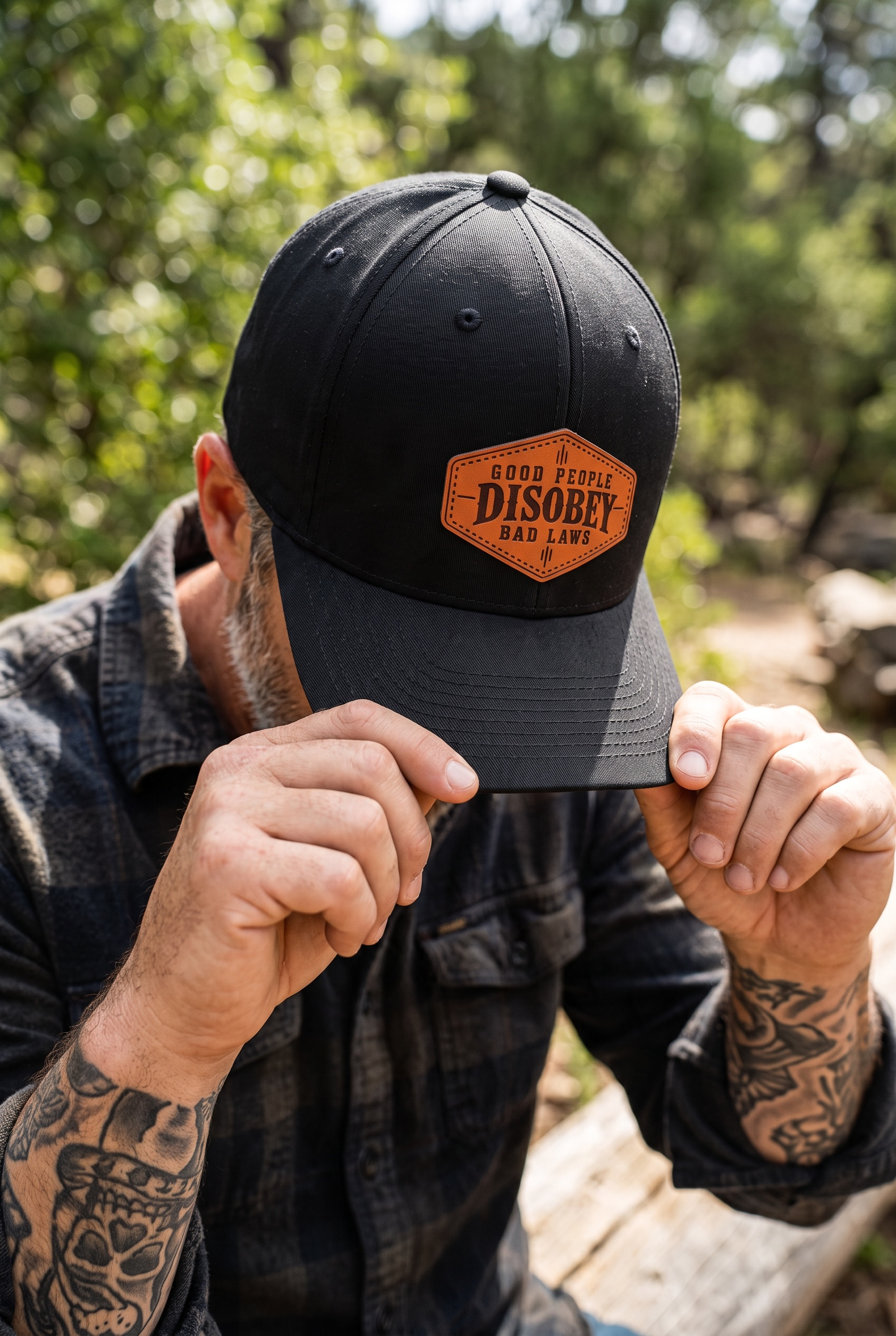 Man wearing a Richardson 112 black trucker hat with a genuine leather Good People Disobey Bad Laws patch by Sundown Mercantile.