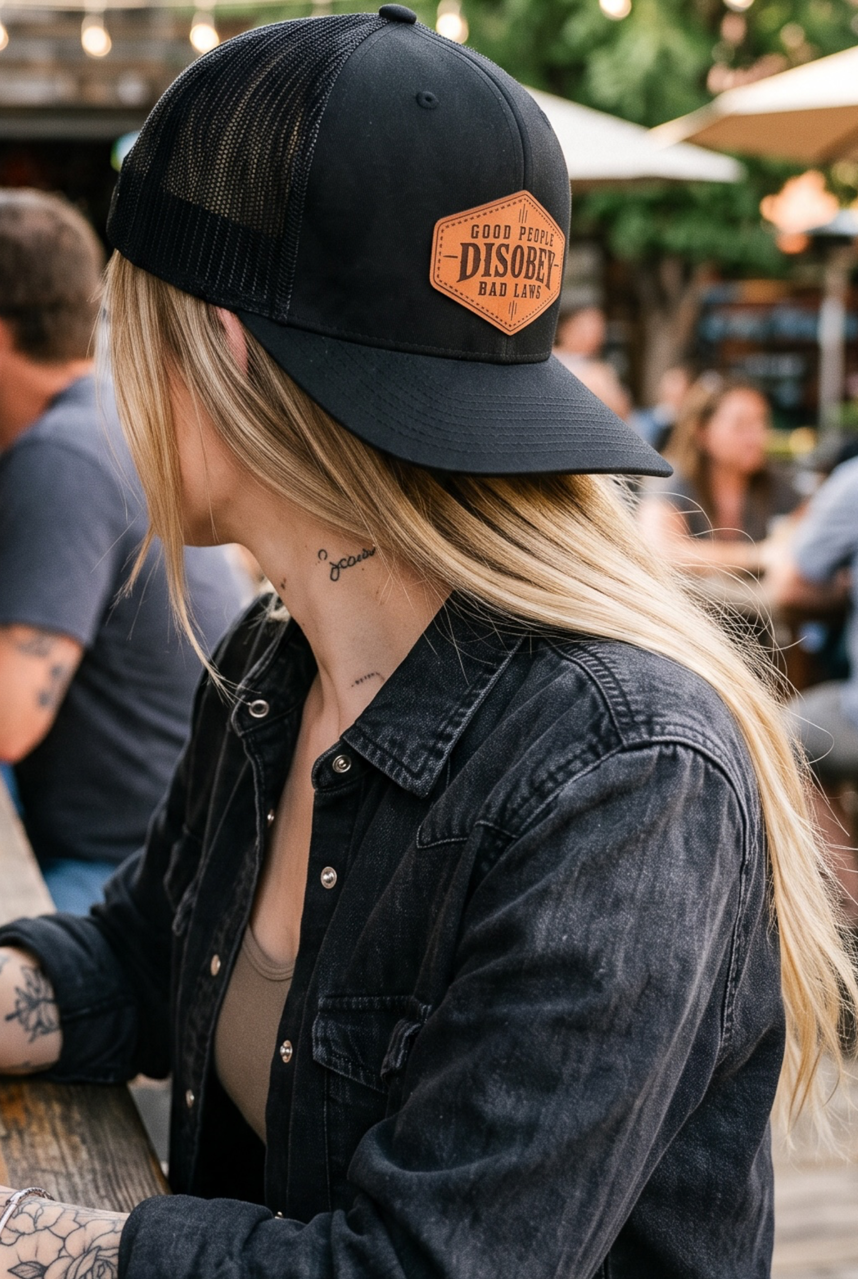 PhotSide profile of a woman wearing a Richardson 112 black hat with a custom laser engraved genuine leather patch by Sundown Mercantile.