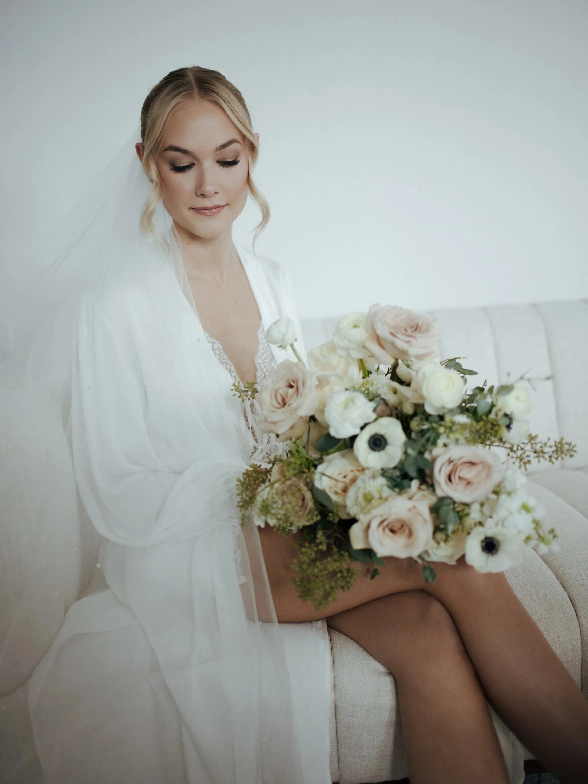 Bridal makeup look with soft glam styling, bride holding pink and white bouquet by window in natural light