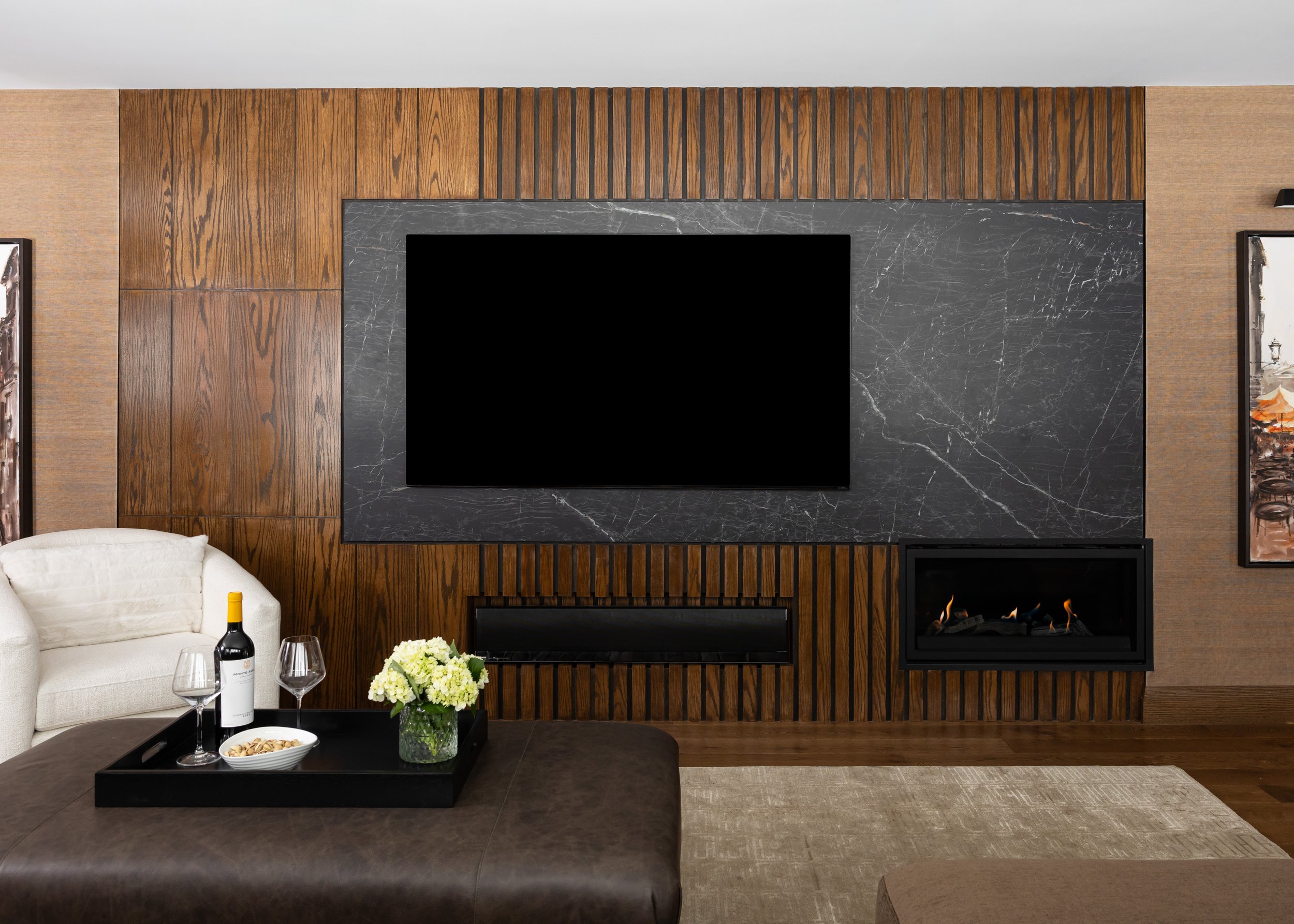 Contemporary living room design by Studio 7 Designs featuring a custom wood slat and black marble TV wall with a built-in linear fireplace, modern furnishings, and ambient luxury decor.