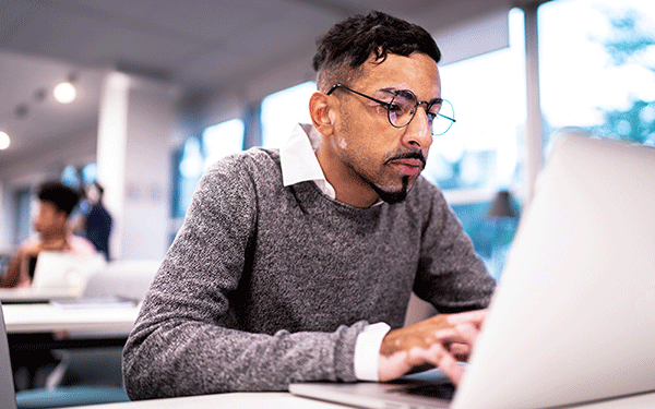 Student in a classroom working on his laptop