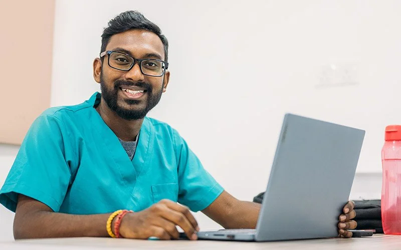 Portrait of a man in scrubs with his laptop