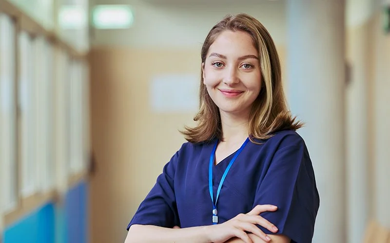 Portrait of a young, smiling, female nurse in a hallway