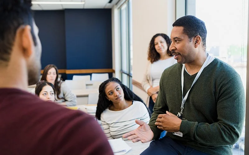 College professor talking to students gathered near to him