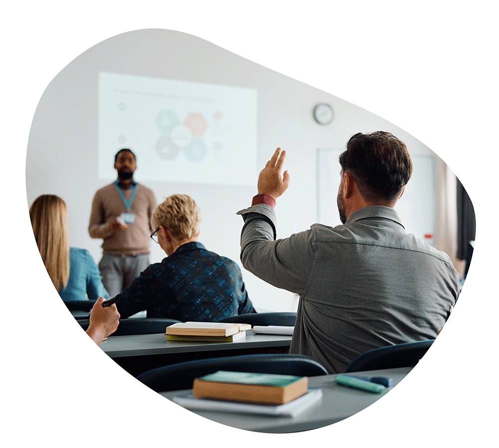 Student raising hand in a college classroom setting.