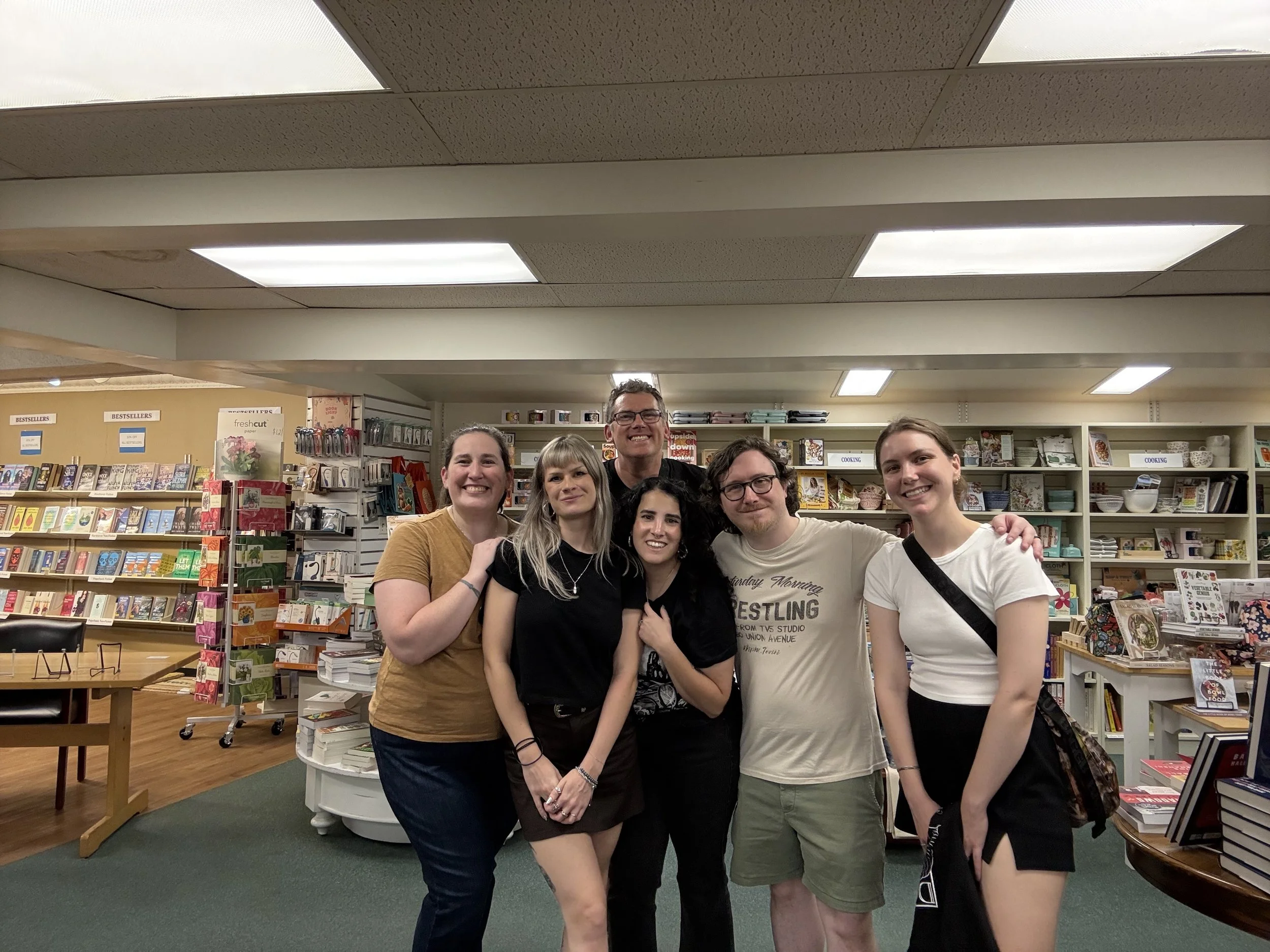 Group of six smiling people standing together inside a bookstore for Dark Ink.