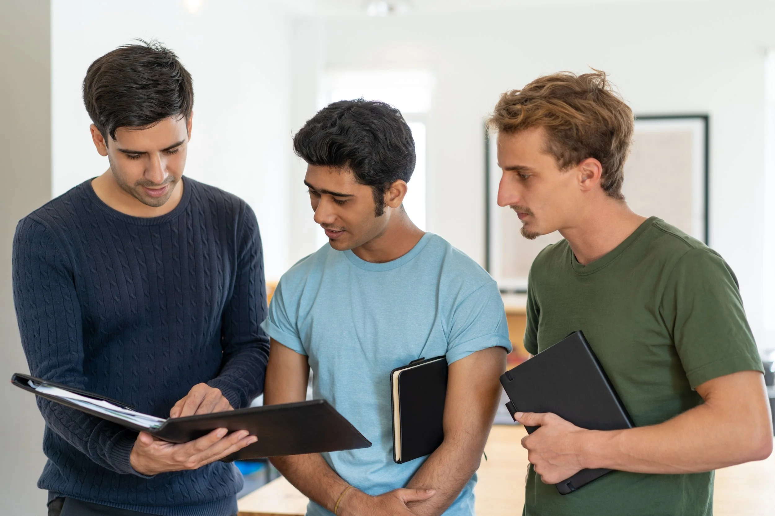 A mentor teaching his teen mentees and pointing at his paper - Bridge The Gap