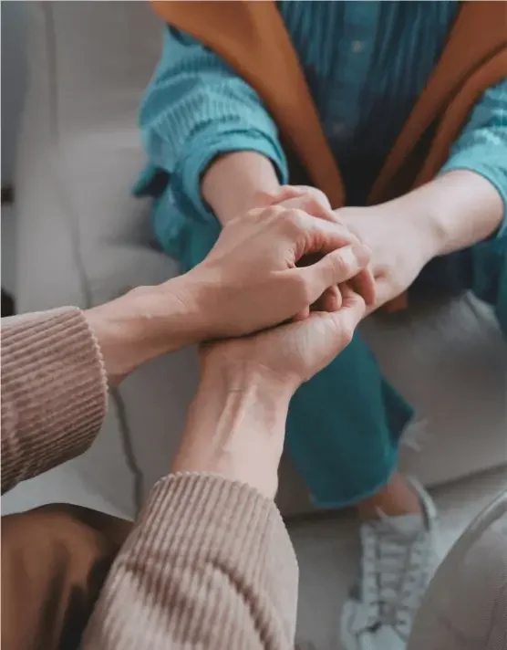 Therapist holding a clients hand during a therapeutic mentorship session - Bridge The Gap