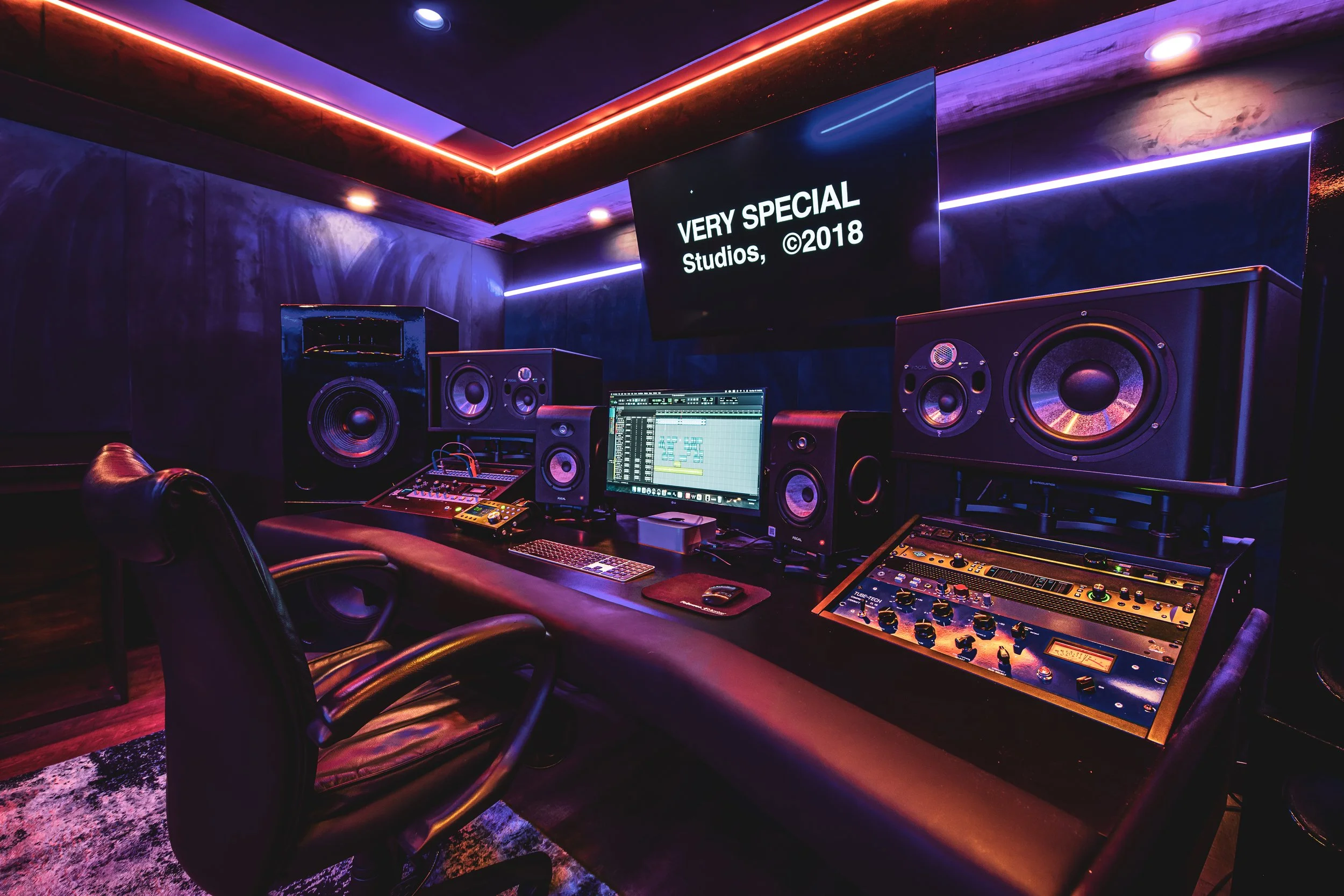 Recording studio with sound equipment, monitors, speakers, and mood lighting.