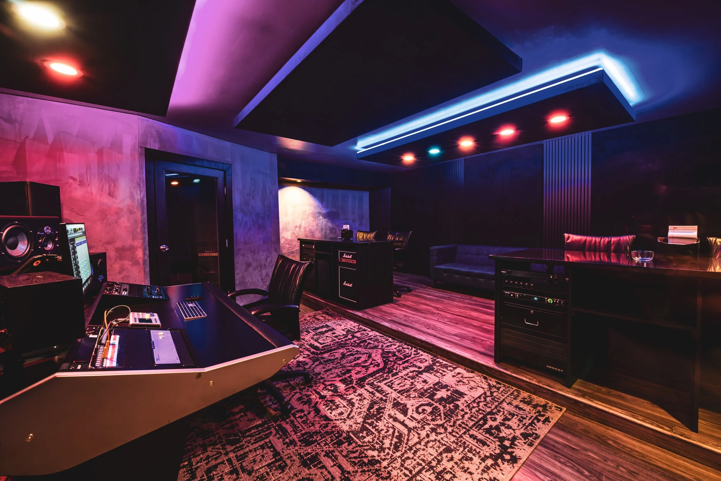 Modern music recording studio with mixing console and colorful lighting