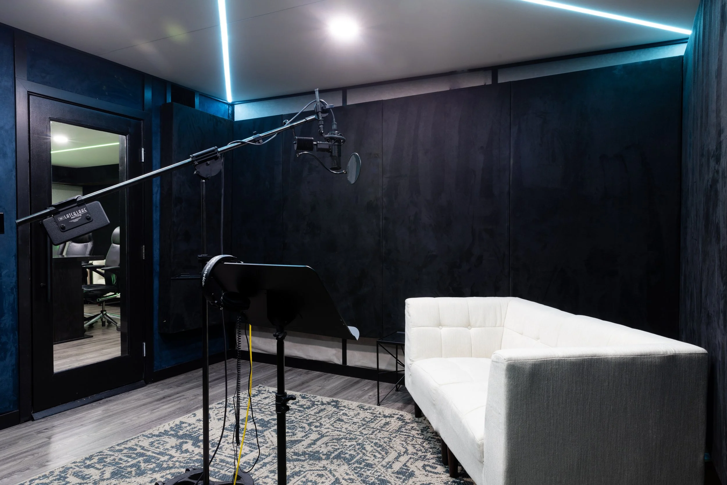 Soundproof recording studio with microphone setup, white couch, and acoustic panels.