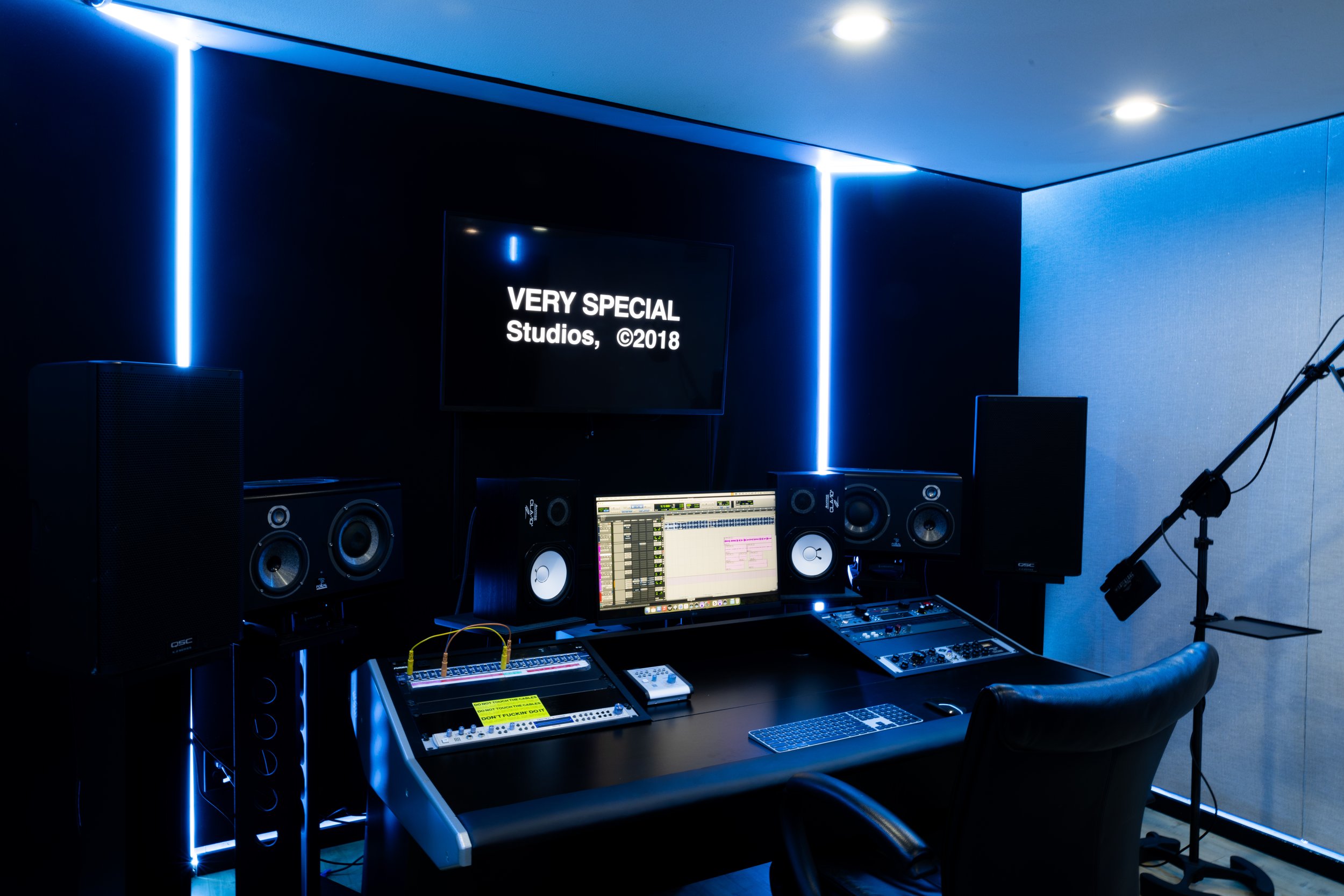Modern music recording studio with speakers, computer, and microphone stand.