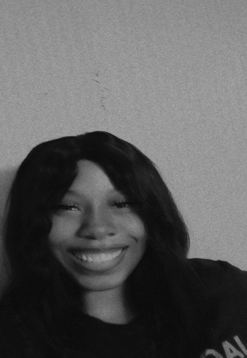 Black and white selfie of a woman smiling with dark, shoulder-length hair and wearing a dark top.