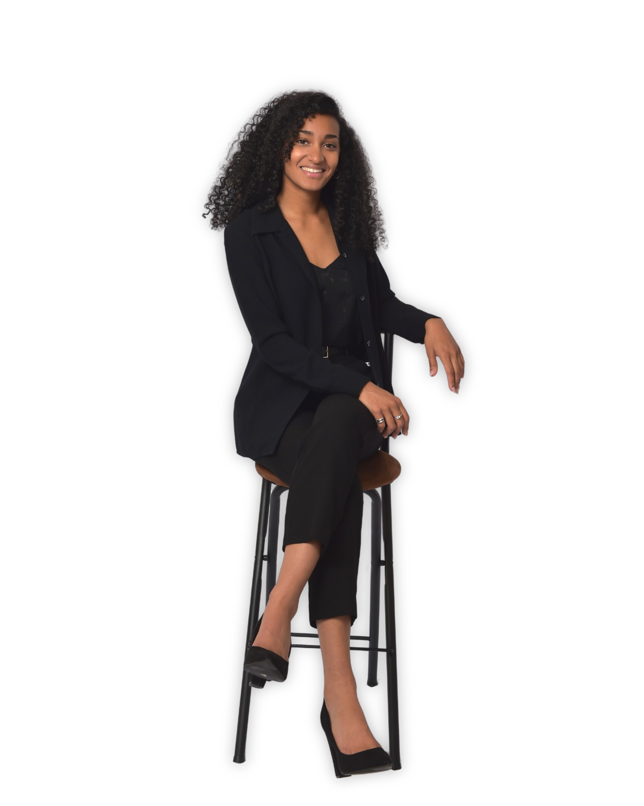A transparent png image of MacKenzie (@zenkenzie) sitting on a tall stool with one leg crossed over the other, smiling at the camera.