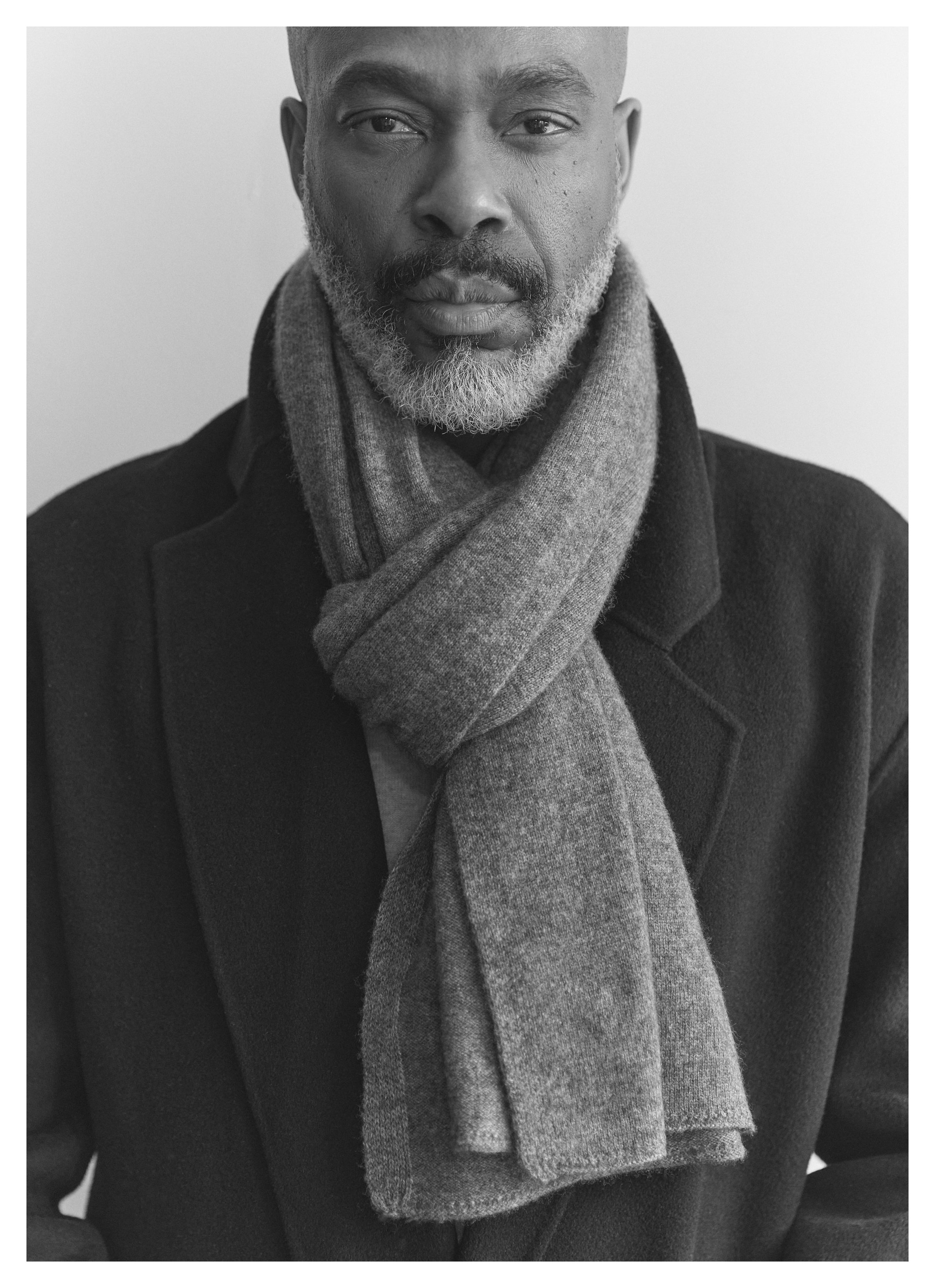 Portrait en noir et blanc d'un homme portant un manteau et une écharpe.