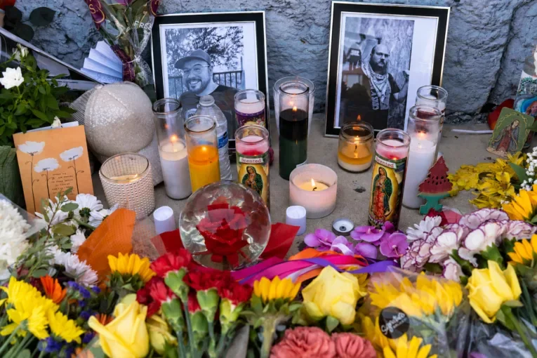 A memorial altar with flowers, candles, and photographs of two men.