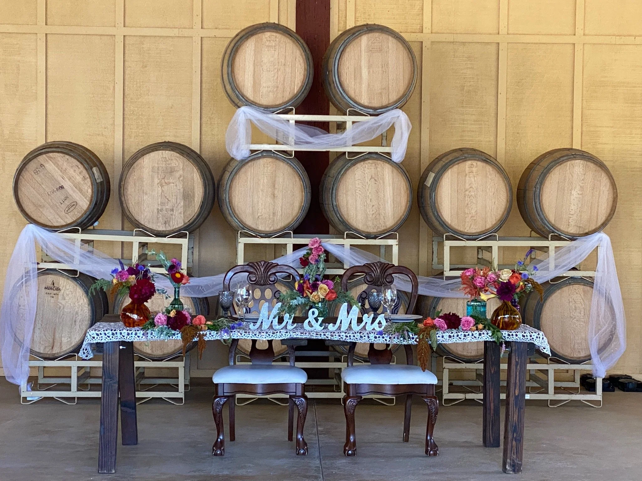 Wine barrel wedding decor and farmhouse sweetheart table at Four Sisters Ranch Winery wedding venue in Paso Robles, California