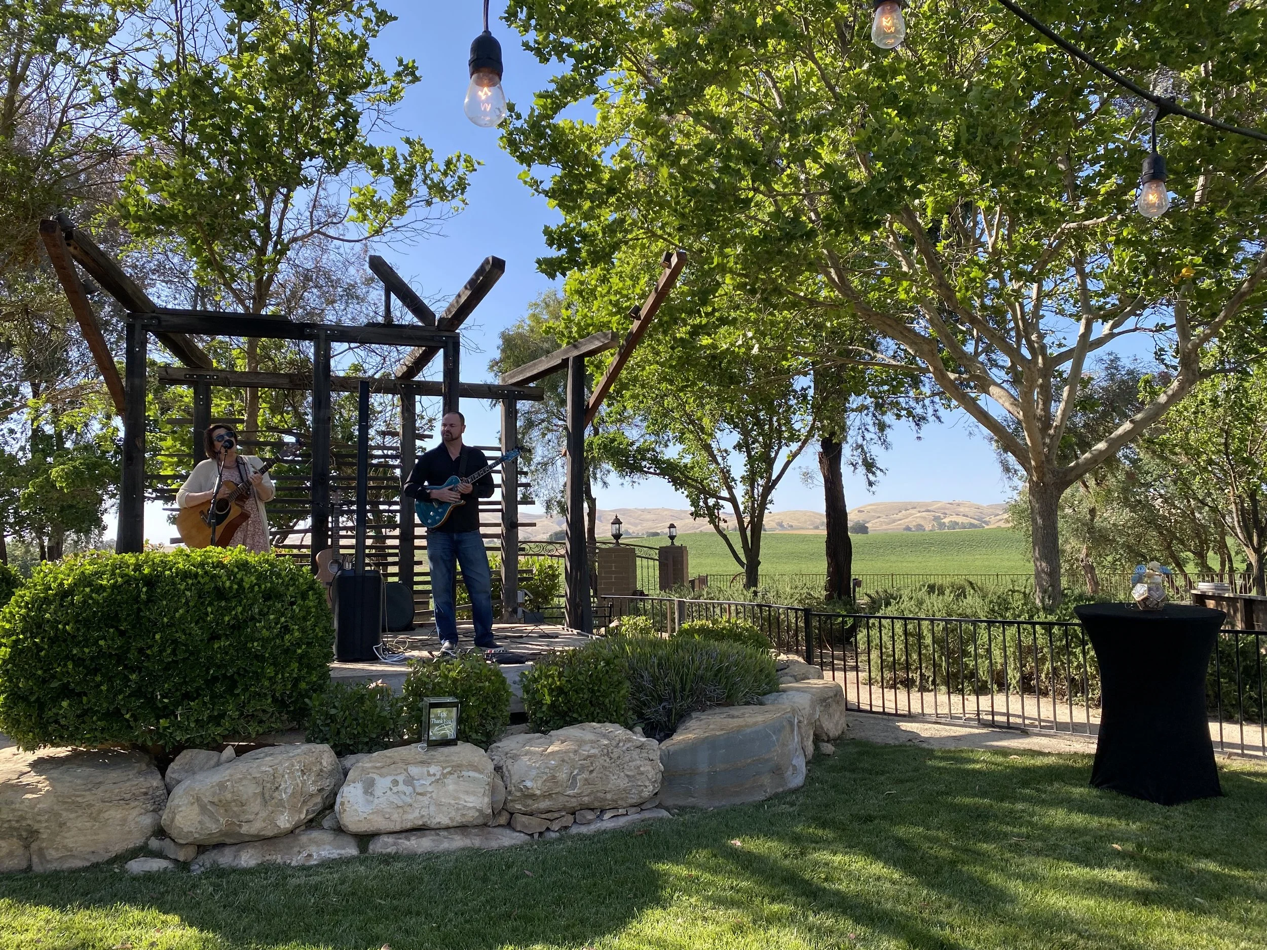Outdoor stage at Four Sisters Ranch Vineyards & Winery in Paso Robles with wine country views of vineyards and hills. 