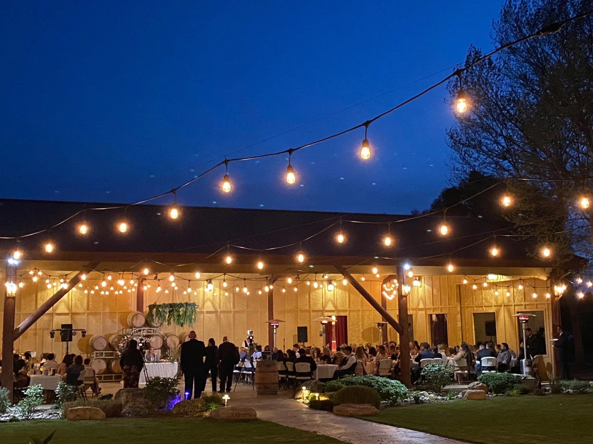 Twilight under the bistro lights - wedding reception at Four Sisters Ranch Vineyards & Winery wedding barn style wedding and event venue in Paso Robles, California