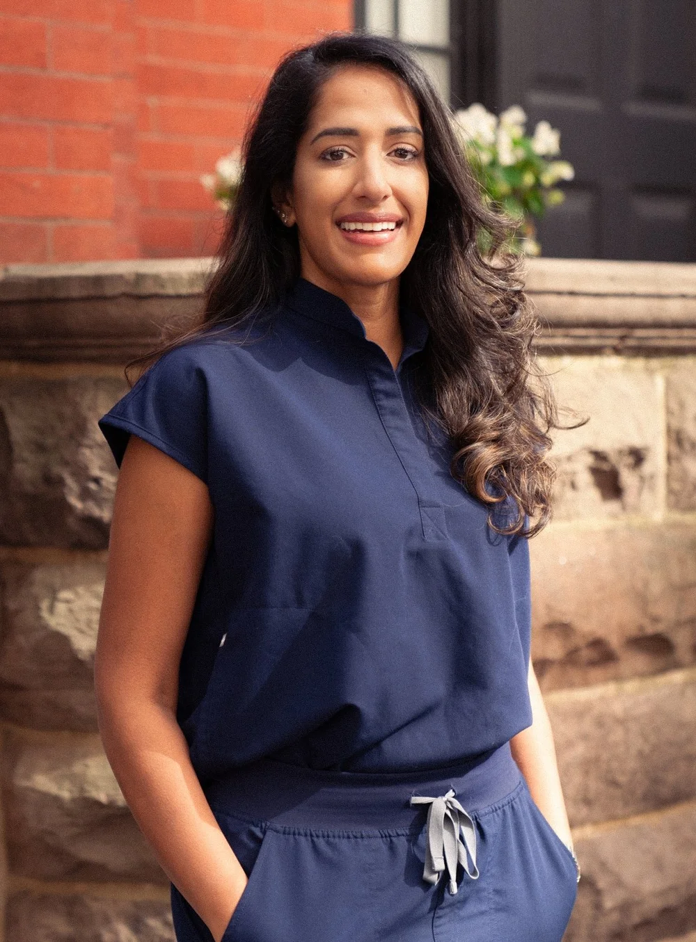 Dr. Ayushi Dixit smiling in navy scrubs outside her Upper East Side office