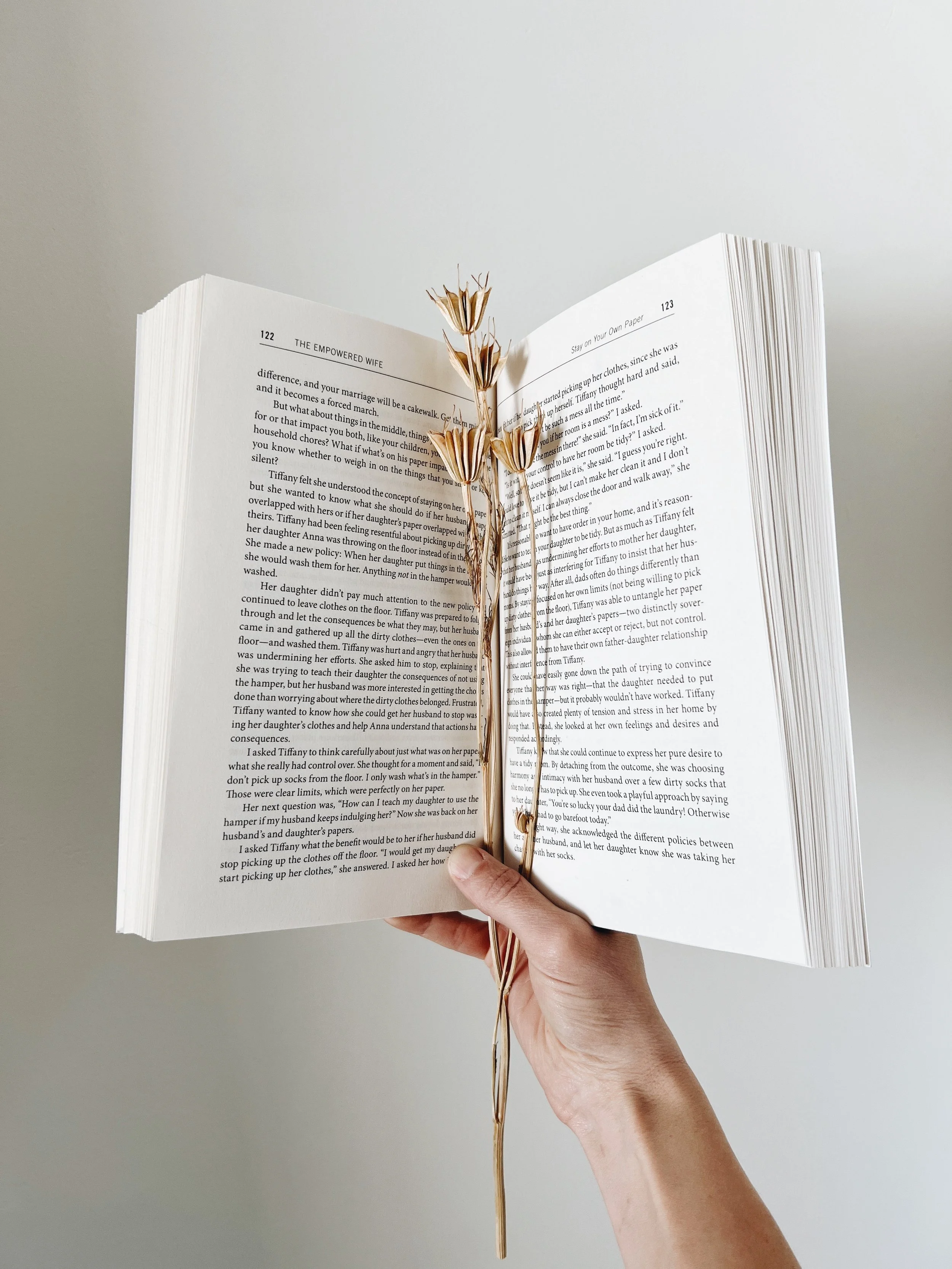 A hand holds open a book with florals down the middle, if this work aligns, let's work together