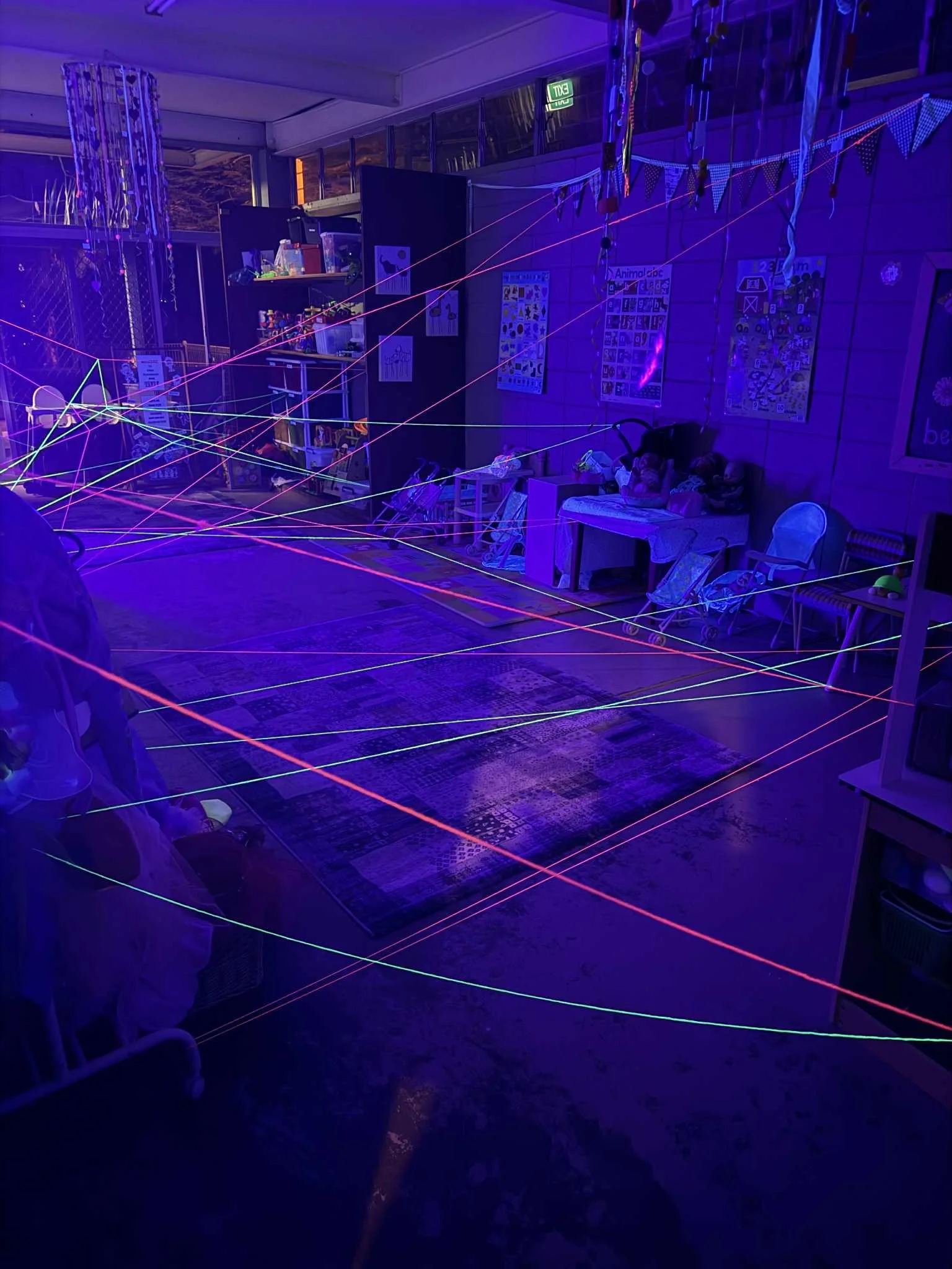 Group of people standing outdoors near a fence at night, watching people playing a game.