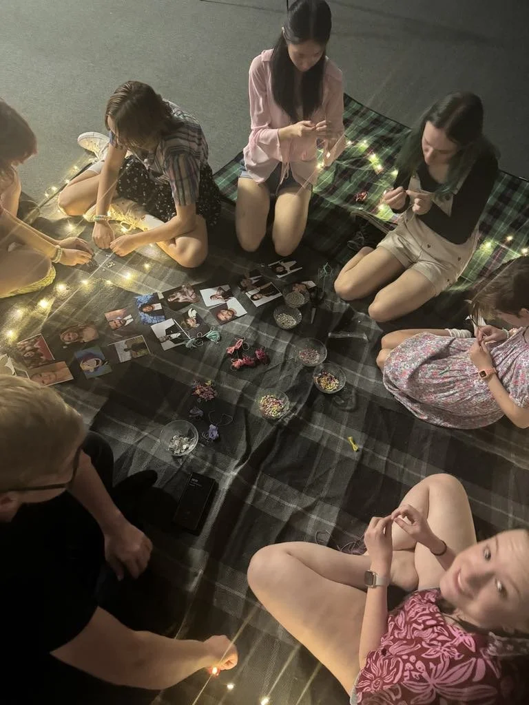 People playing beach volleyball on sand court surrounded by netting.