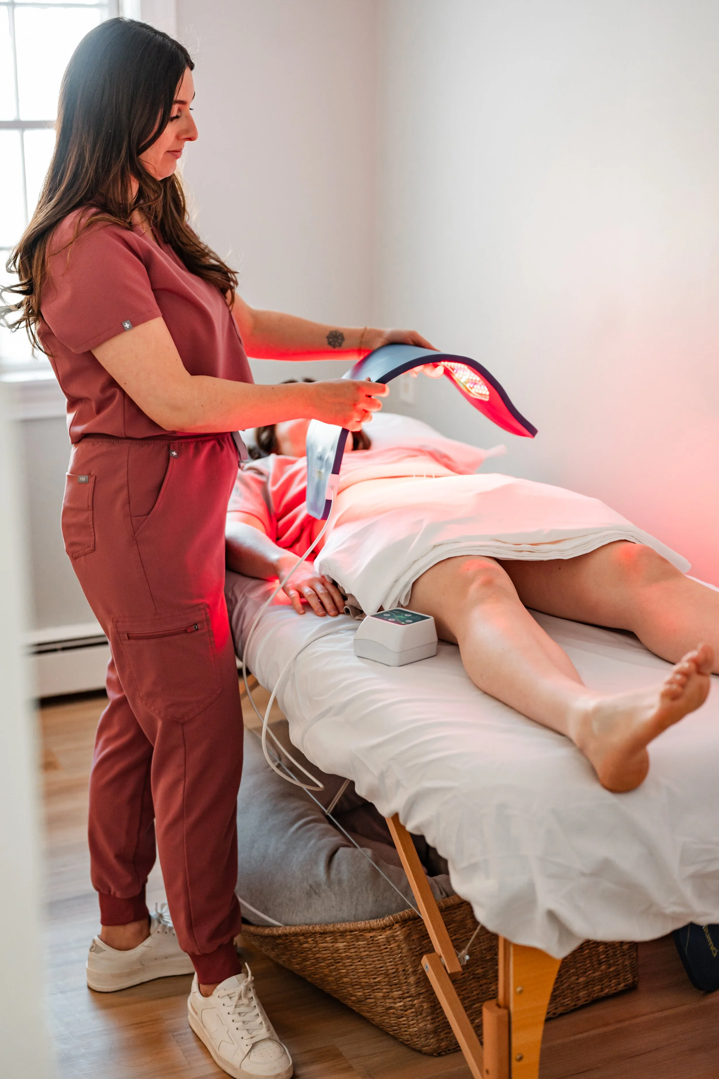 Red light therapy applied to the legs alongside acupuncture treatment at The Violette House in Groton, MA
