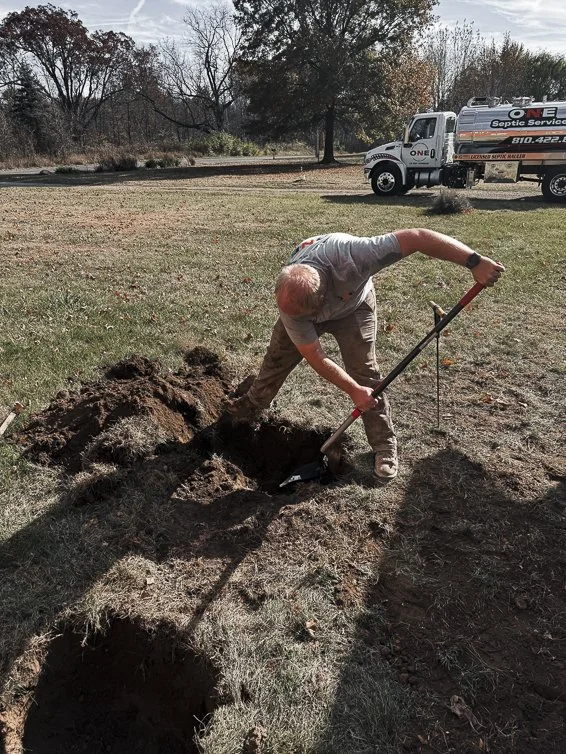 Andrew from ONE Septic Services uncovering a septic tank lid in Genesee County, ensuring essential septic tank pumping for long-lasting systems.
