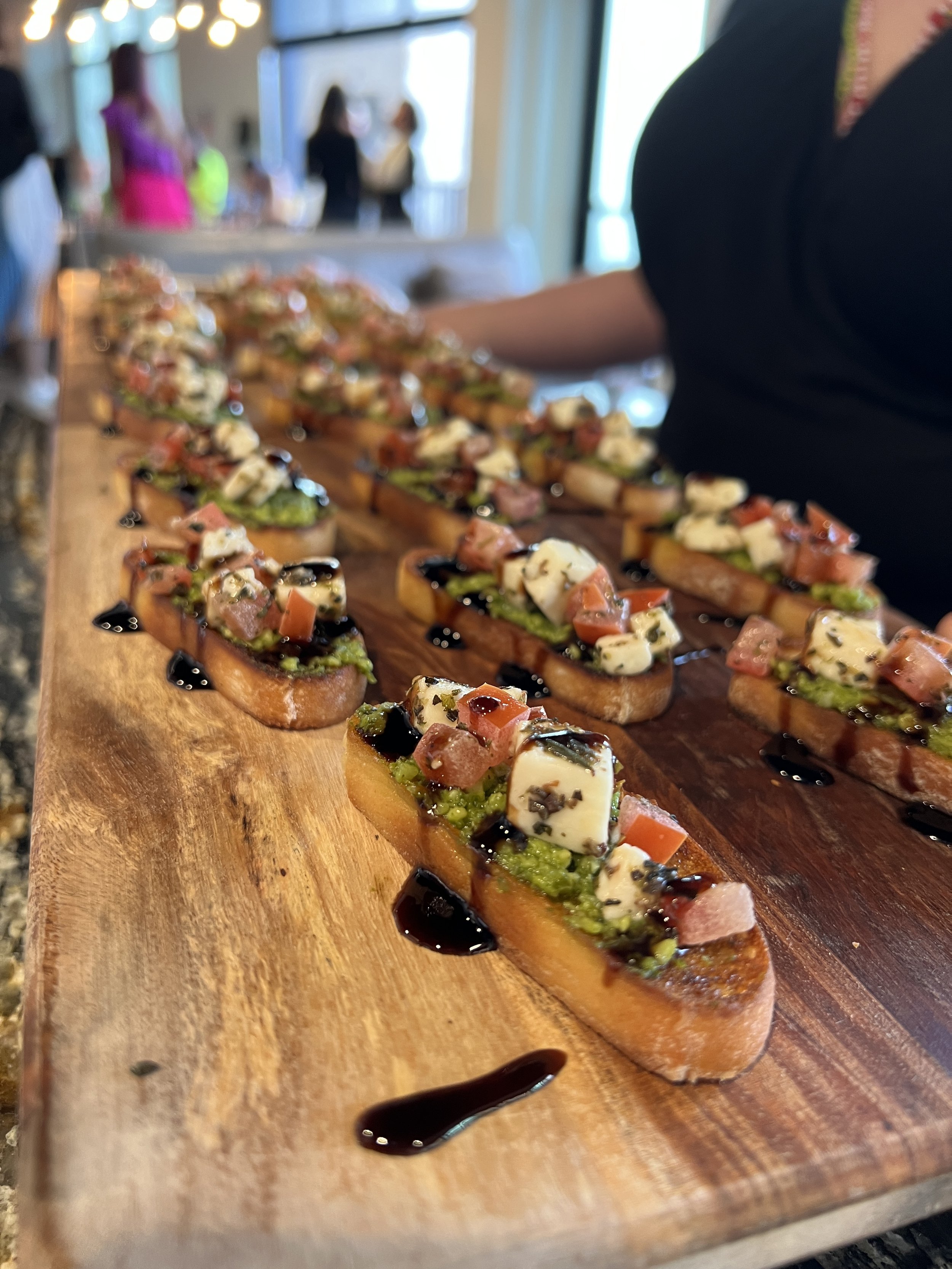 Assorted bruschetta on a wooden serving board at a catering event.