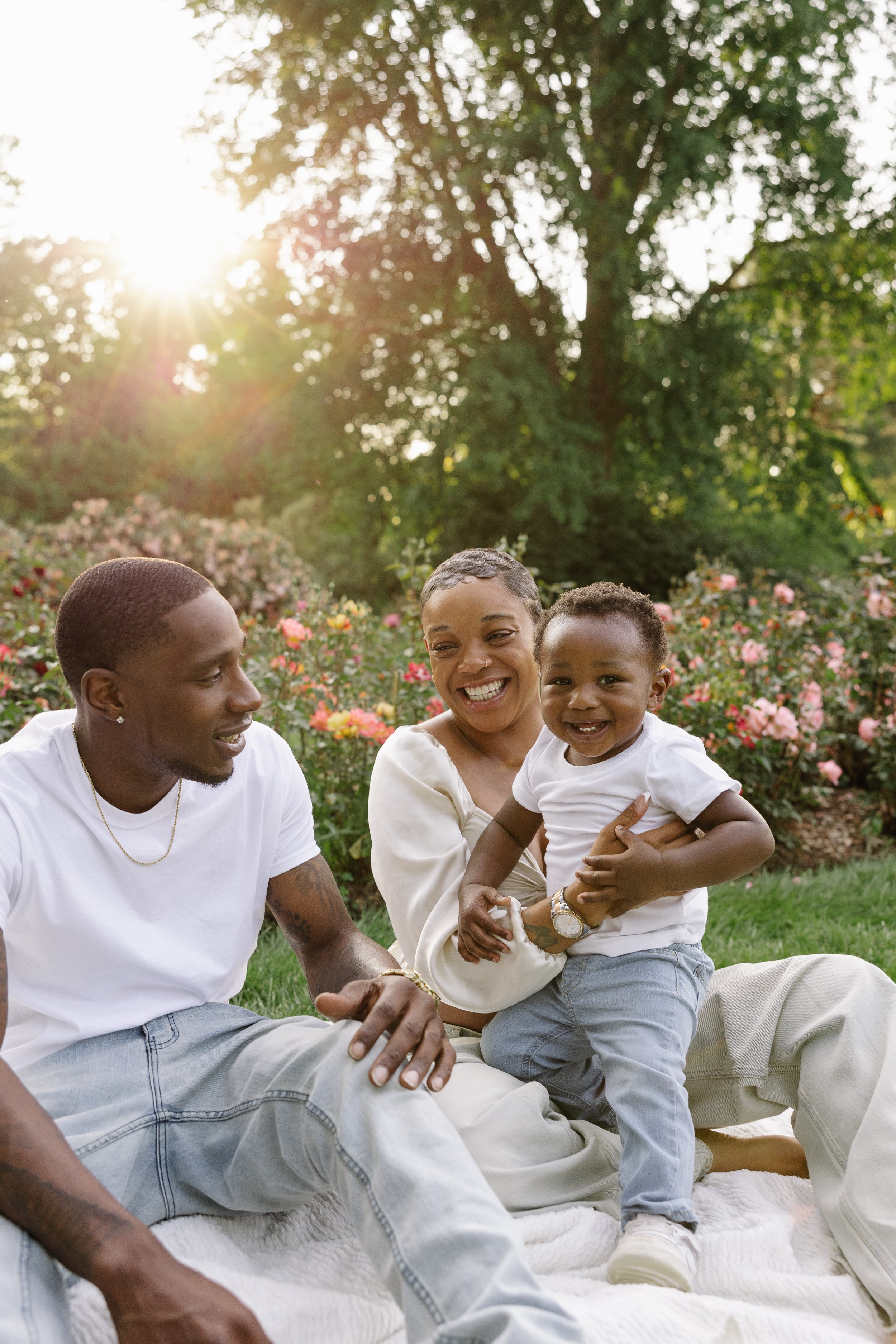 man woman and child smiling sitting in a park