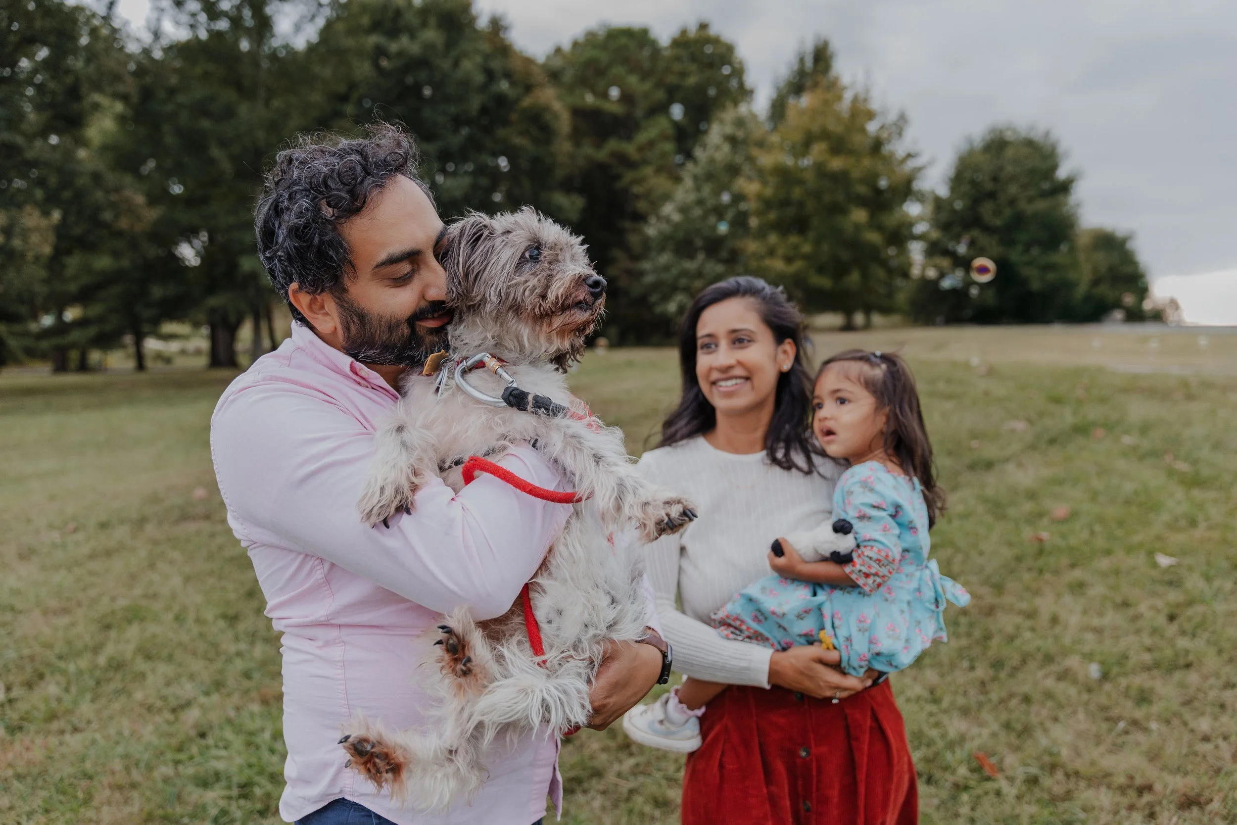Family with toddler and dog smile at each other during spring family photos in Durham, NC.
