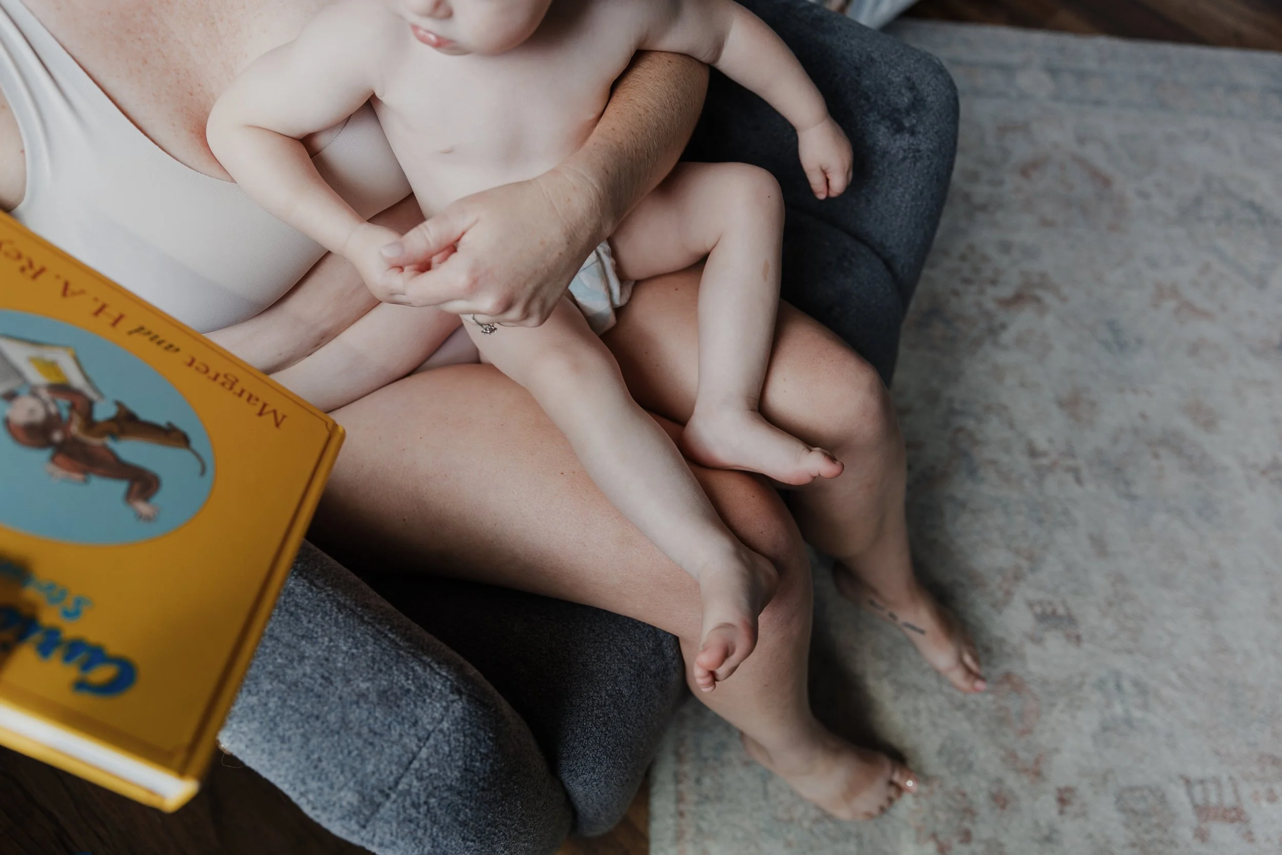 A mom sits skin-to-skin with her toddler during a professional photosession celebrating motherhood at home in Raleigh, NC.