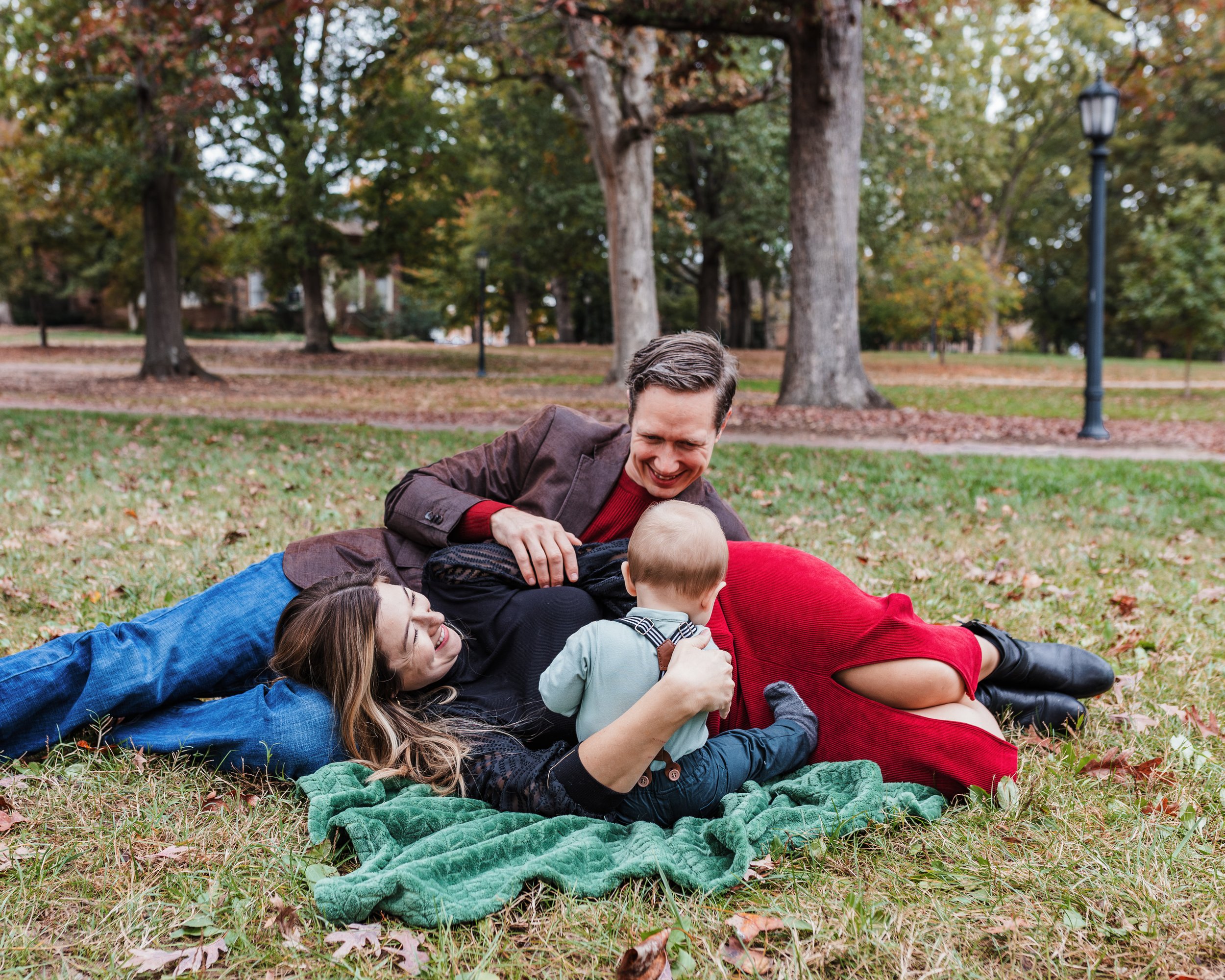 Couple laugh on the grass with baby during lifestyle family photo session at UNC.