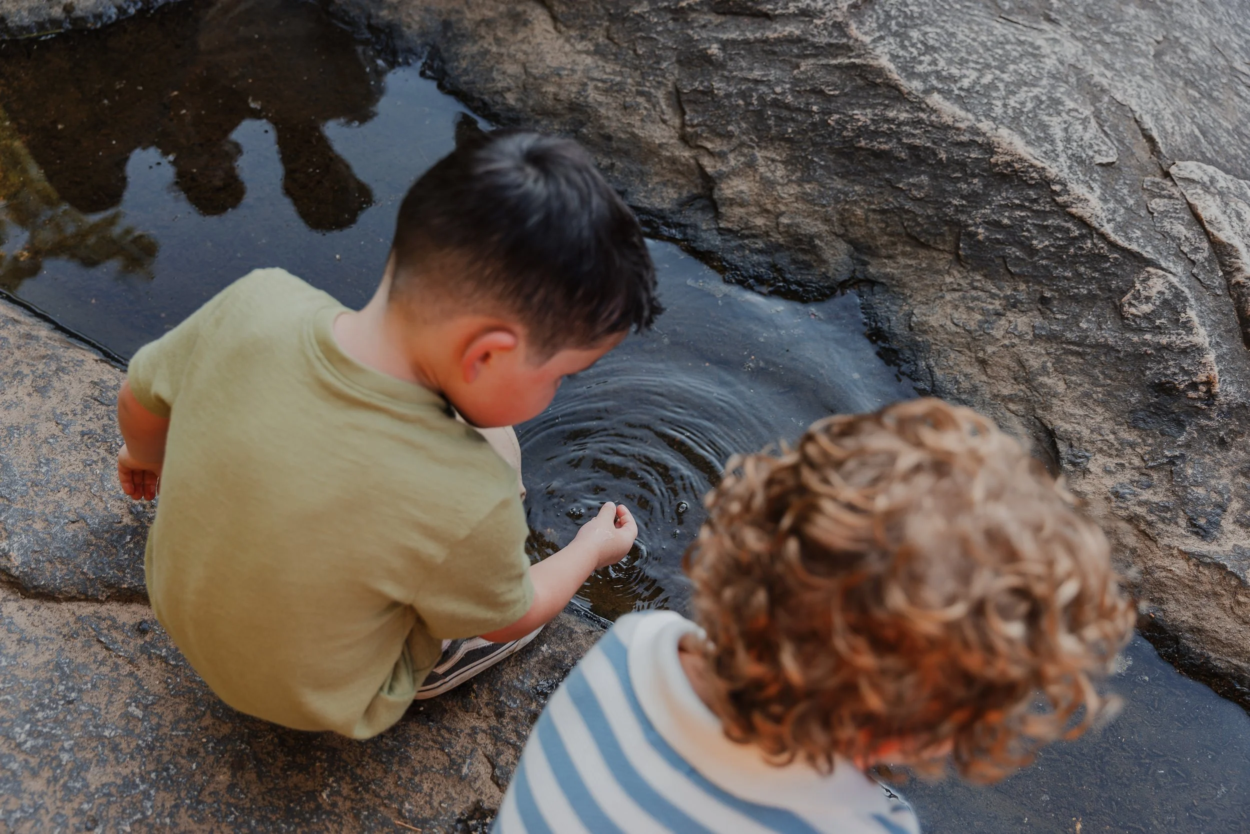 Kids look at their reflection in a puddle during family photos at Yates Mill in Raleigh, NC.